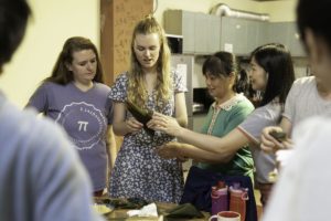 A group of women gathers around an object held up in a kitchen area