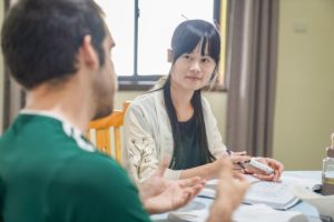 A student gestures to his teacher across a table during class