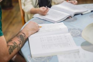 Close-up of a student's tattooed arm writing in a workbook