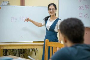 A teacher points to characters on a whiteboard during a class