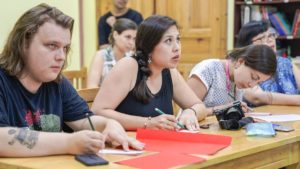 Students work on red paper crafts at a long table