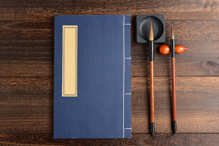 chinese notebook and calligraphy pens on wooden table