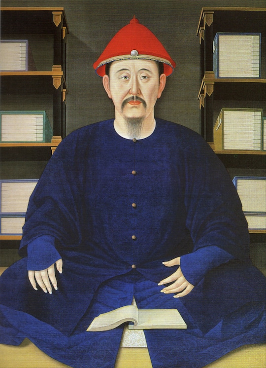 emperador kangxi sentado con las piernas cruzadas frente a libros