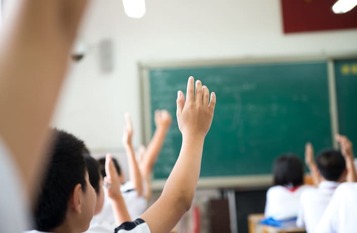 escolares chinos levantando la mano
