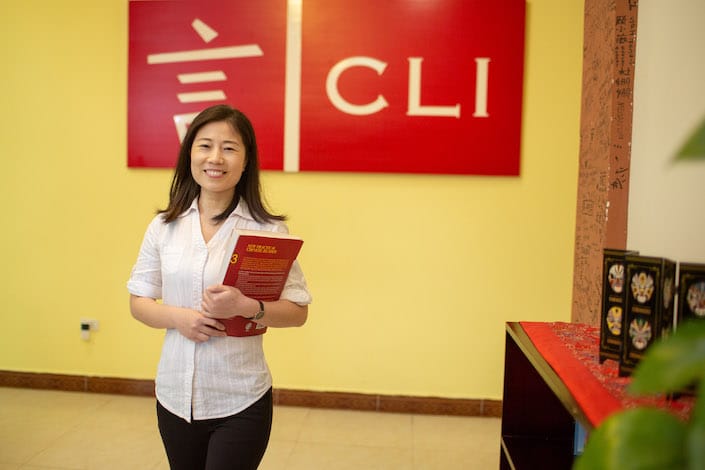professeur chinois debout devant le logo de l'école