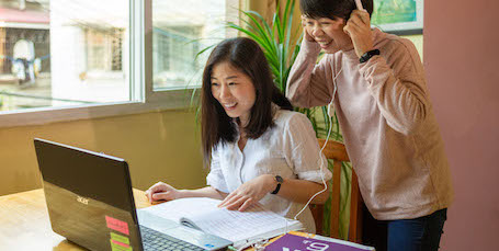 two chinese teachers looking at a laptop in a small classroom