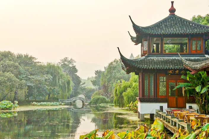 a traditional Chinese building and bridge on a lake