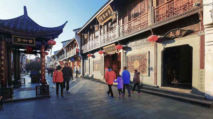 붉은 등으로 장식된 중국 전통 쇼핑 거리를 걷는 사람들