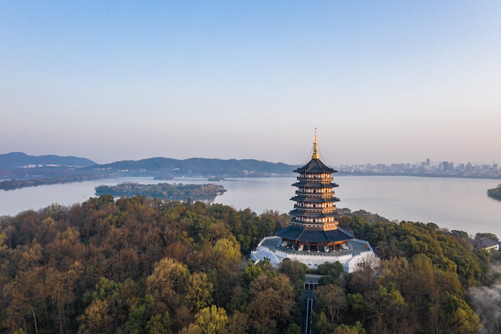 Leifeng Pagoda surrounded by trees with Hangzhou's West Lake behind it