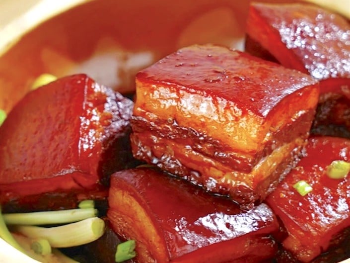 several blocks of dongpo pork showing pork fat and layers of meat garnished with spring onions