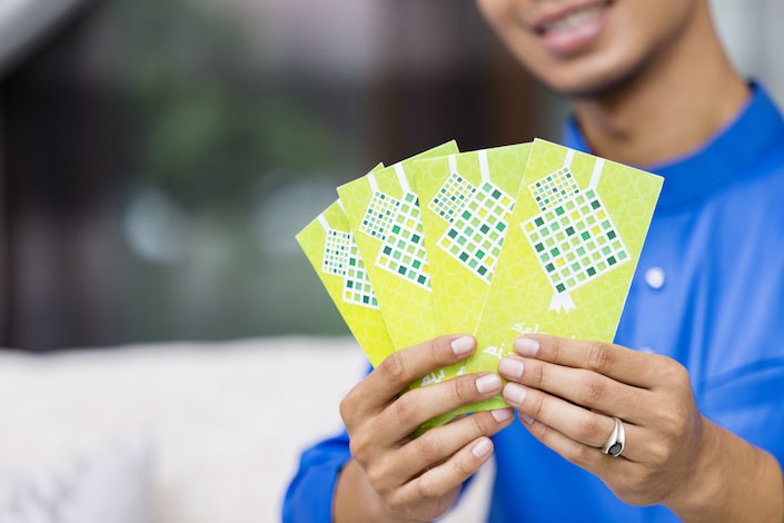 muslim man holding green envelopes