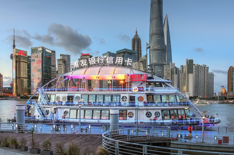 Ferry et bateau de croisière fluvial flashy amarré sur le Bund avec en arrière-plan les toits de Pudong à Shanghai Chine