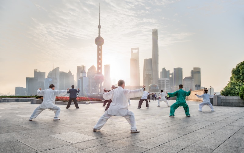 Group of people practicing Tai Chi Quan on the Bund in Shanghai with modern skyscrapers in the background