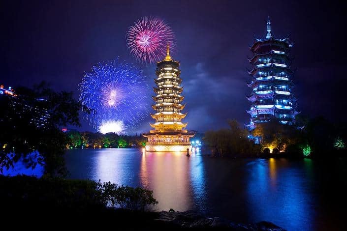 the sun and moon pagodas in Guilin, China with fireworks going off in the background