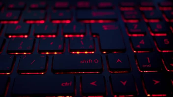计算机键盘上的按键部分呈黑色，下方闪烁着橙红色的灯光