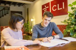 A teacher and student study a textbook under the CLI sign
