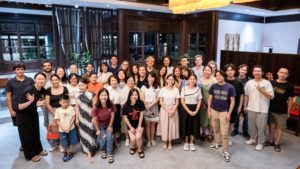 A large group poses together in a wood-paneled lobby