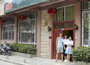 Three people stand in the doorway of the CLI Center beneath red lanterns