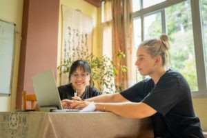A teacher and student work together at a desk by a window