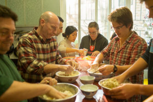 People mix dumpling filling in bowls around a table