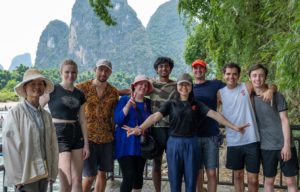 A group in sun hats and caps poses together before karst peaks