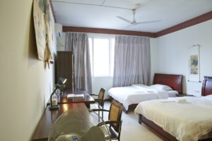 A bright room with two beds and a desk