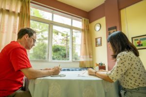 A student writes characters with a teacher at a table