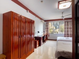 A room with a tall wooden wardrobe and a bed