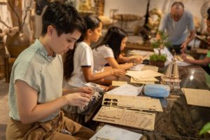 People assemble wooden joinery models around a workshop table