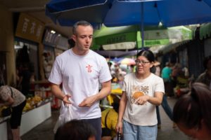 A man and a woman walk and talk through a covered market