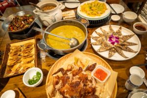 A table spread with soup, dumplings and roast duck