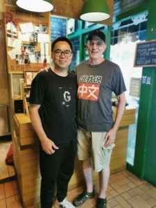 Two men pose together in a shop
