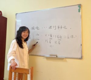 A teacher writes Chinese on a whiteboard