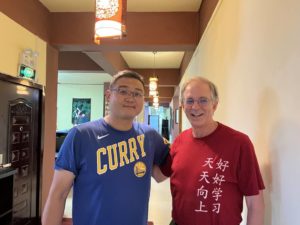Two men pose together in a hallway