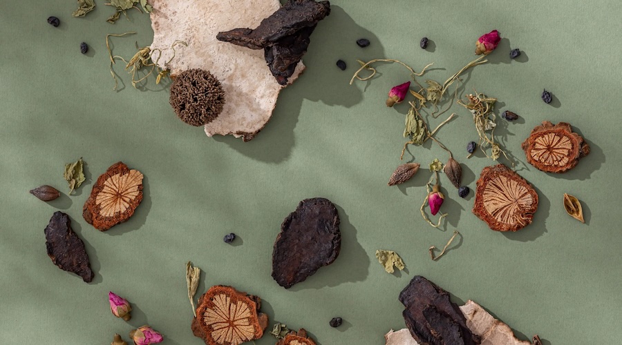 A selection of Chinese skincare products displayed alongside traditional herbal ingredients