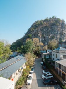 A karst hill rises above rooftops and parked cars on a quiet street