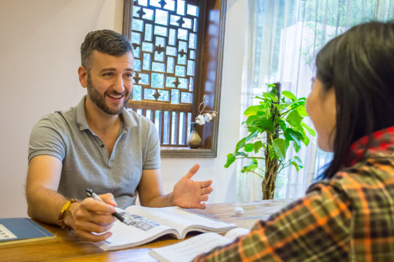 Un étudiant souriant pendant un cours individuel près d'une fenêtre à treillis