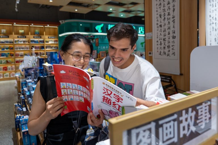 Un professeur de CLI et un étudiant riant devant un cahier de caractères dans une librairie