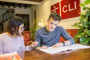 Two people study a workbook together below the CLI wall sign