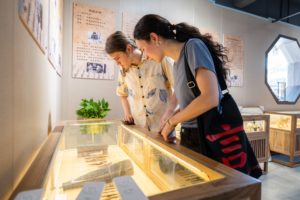 Visitors lean over a glass display case in an exhibition hall