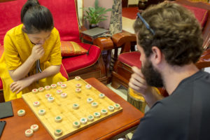 Two people play Chinese chess at a wooden board
