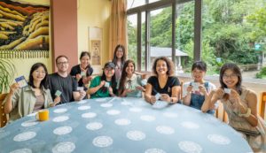 A group smiles and holds up small cards around a large round table