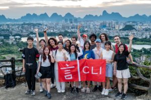 A cheering group holds a CLI banner above Guilin's skyline at sunset
