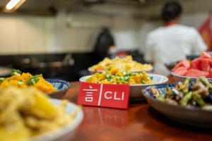 Bowls of home-style dishes beside a CLI table card