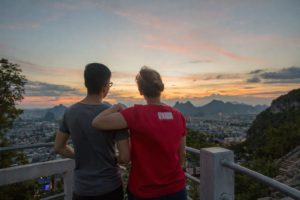 Two people look out over the city and karst peaks at sunset