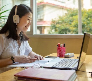 CLI teacher giving an online Chinese lesson from a laptop at a desk