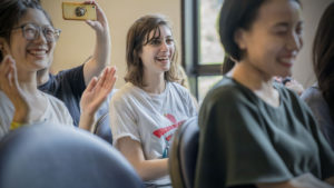Guests smile and applaud while one takes a photo with a phone
