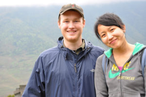 Two people smile at a misty mountain viewpoint