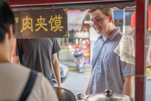 A smiling customer orders at a street food stall
