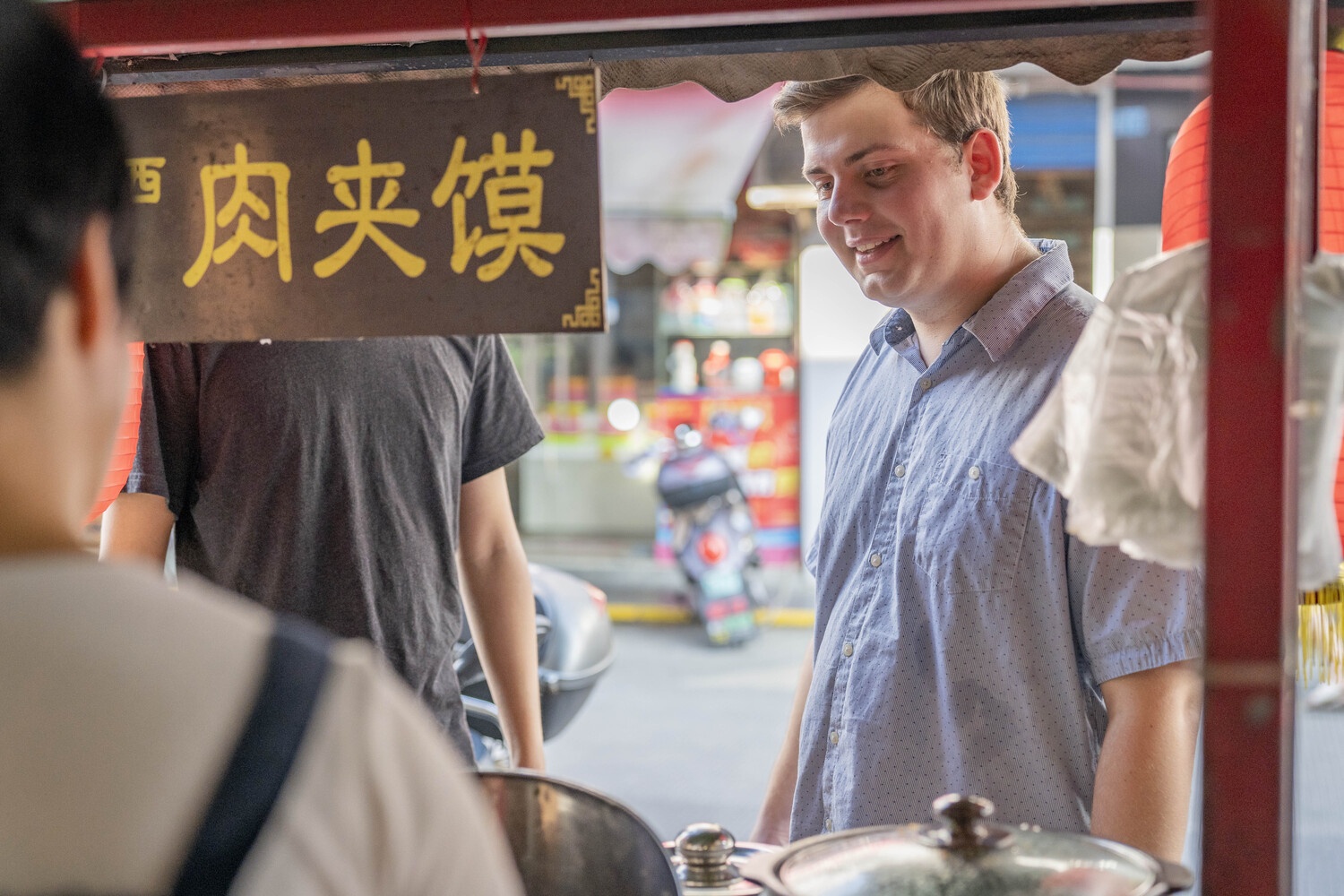 Customer smiling while ordering from a small street food stall